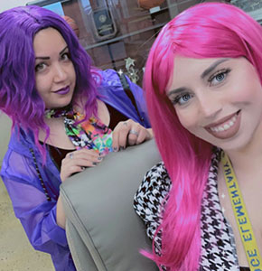 Two teachers wearing a purple wig and a pink wig